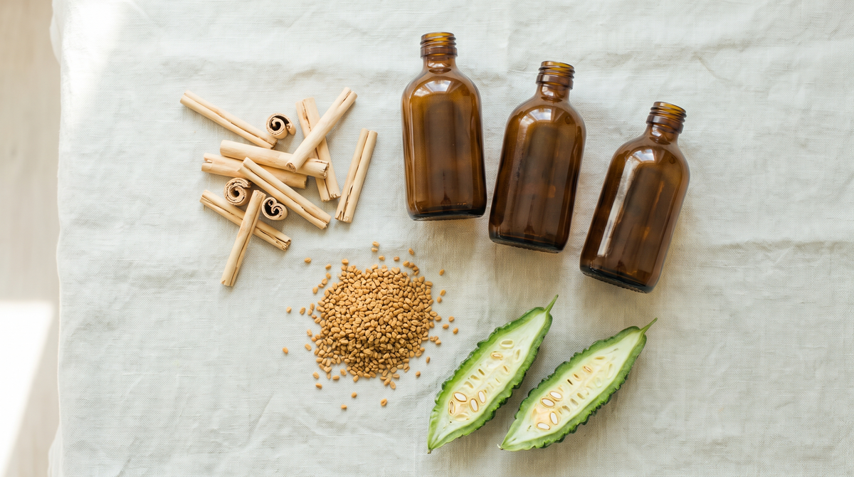 Three unlabelled amber glass supplement bottles on linen beside Ceylon cinnamon quills, a heap of fenugreek seeds and two halves of a ridged green bitter melon