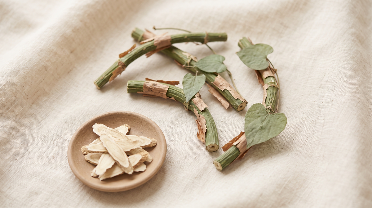 Dried Guduchi vine stem pieces with heart-shaped leaves and a small dish of sliced stem on cream linen