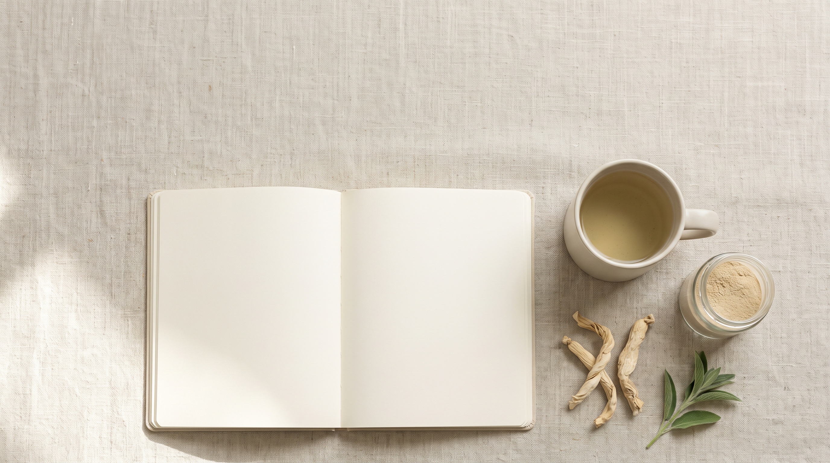 An open blank notebook, a mug of herbal tea, a jar of pale root powder and dried root pieces on a linen surface in soft morning light