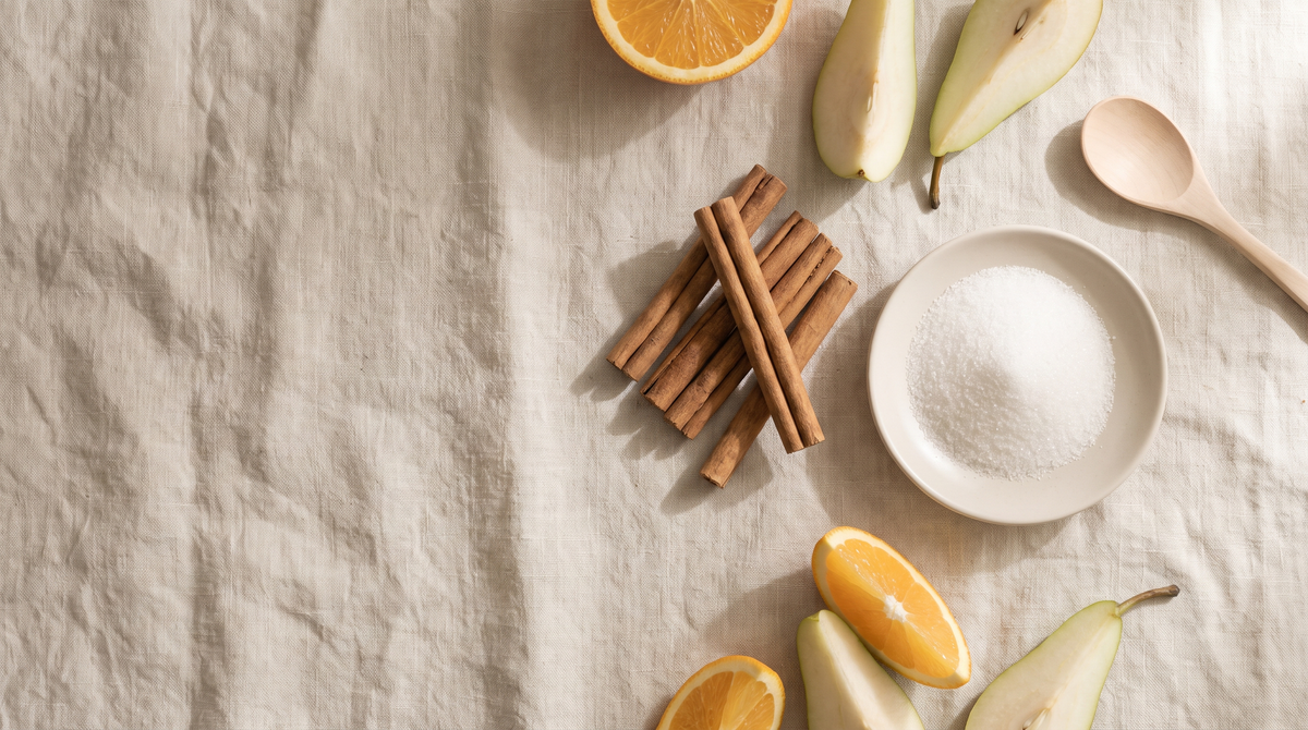 Ceylon cinnamon quills, a small dish of white sugar and fresh sliced fruit arranged on a linen table