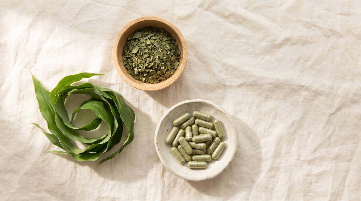 Fresh green Thebu leaves beside a wooden bowl of dried crushed leaf and a ceramic dish of green capsules on cream linen