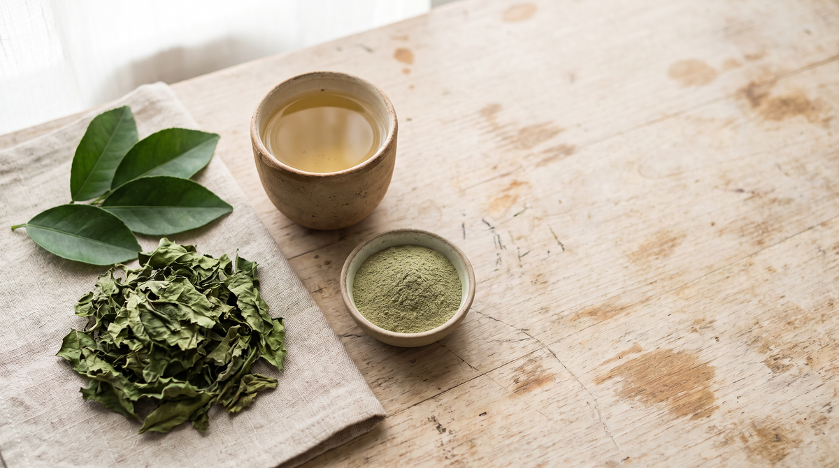 Dried and fresh Yaki Narang leaves, a bowl of leaf powder and a clay cup of pale golden tea on a linen napkin