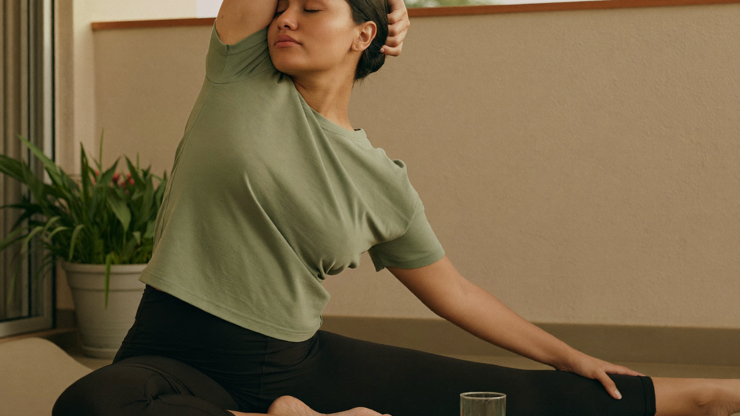 A woman stretching on a yoga mat on a home balcony at dawn, part of a calm 6 AM morning ritual.
